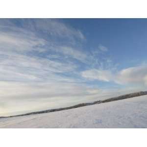 Vast Peaceful Field Covered in Snow with Wispy Clouds in the Sky Above 