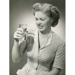 Studio Shot of Woman Grimacing While Looking at Glass of Water 